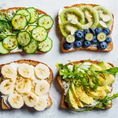 Quatre tartines garnies : concombre et pousses, kiwi et myrtilles, banane et pignons, avocat et roquette. Un régal pour un goûter sain.