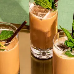 Trois mocktails rafraîchissants à la menthe et au chocolat, servis dans des verres hauts avec de la glace et des pailles foncées.