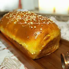 Un pain brioché salé doré, parsemé de graines, sur un plateau en bois. Parfait pour une recette facile et savoureuse.