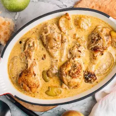 Poularde de Bresse en sauce crémeuse, une recette savoureuse avec des morceaux de poulet dorés et des pommes.