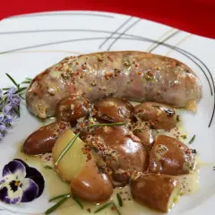 Une andouillette sauce moutarde, accompagnée de pommes de terre grenaille et d'une touche de romarin et de pensée.