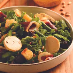 Salade périgourdine : foie gras, magret fumé, asperges vertes, croûtons et olives noires dans un bol.