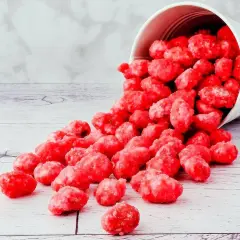 Un seau blanc renversé déverse des bonbons roses brillants, parfaits pour une recette praline rose.