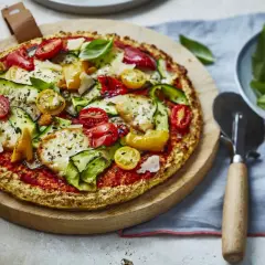 Délicieuse pizza aux légumes frais et fromage, sur une pâte sans gluten, servie sur une planche en bois.