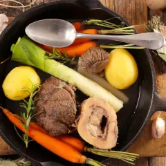 Un pot au feu savoureux, digne d'un journal des femmes, mijote dans une poêle en fonte avec des légumes et de la viande.