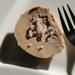 Tranche de foie gras parsemée de gros sel, prête à être dégustée. Une touche d'acidité subtile pour un goût inoubliable.