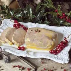 Un foie gras prêt à être dégusté pour Noël, accompagné de pain d'épices et de fruits secs. La question "quand faire le foie gras pour Noël" est résolue avec cette belle présentation.