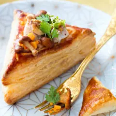Délicieux feuilleté de ris de veau garni de champignons et de légumes croquants, servi sur une assiette ornée.