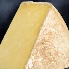 Gros morceau de fromage à pâte dure, jaune pâle, avec une croûte naturelle. Parfait pour la fondue ou un plateau de fromage de Noël.