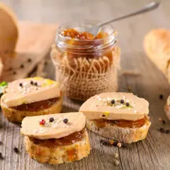Tranches de pain garnies de foie gras et de confiture, avec un pain à côté. Le foie gras calories est un sujet de discussion, mais ce délice est irrésistible.