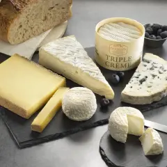 Plateau de fromages variés, dont un bleu et un triple crème, accompagnés de pain artisanal. Un délice pour les amateurs de fromage fort en goût.
