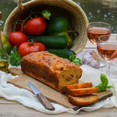 Un délicieux cake ratatouille, garni de légumes frais, d'huile d'olive et de vin rosé, prêt à être dégusté.