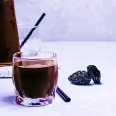 Un verre de jus de pruneau, quelques pruneaux secs et une carafe. Un vrai plaisir pour le temps d'un jus de pruneau.