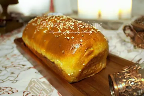 Un pain brioché salé doré, parsemé de graines, sur un plateau en bois. Parfait pour une recette facile et savoureuse.