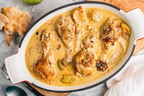 Poularde de Bresse en sauce crémeuse, une recette savoureuse avec des morceaux de poulet dorés et des pommes.