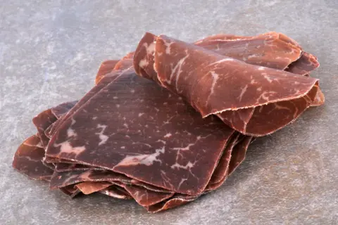 Fines tranches de viande de grison, d'origine suisse, avec leur persillage caractéristique.