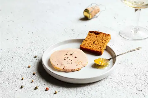 Tranche de foie gras sur assiette avec pain d'épices et confiture. La question "foie gras à partir de quel âge" reste ouverte.