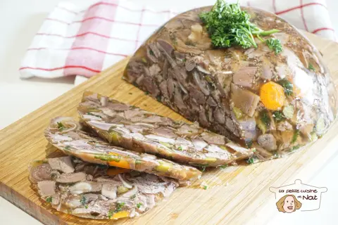 Tranche de fromage de tête, un plat traditionnel à base de viande et de légumes en gelée, garni de persil frais.