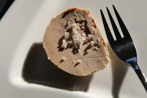 Tranche de foie gras parsemée de gros sel, prête à être dégustée. Une touche d'acidité subtile pour un goût inoubliable.