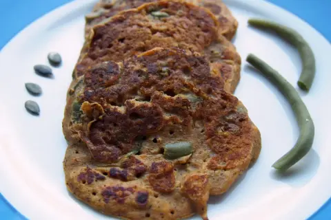 Galettes de patate douce sans gluten, parsemées de graines de courge, avec des haricots verts.