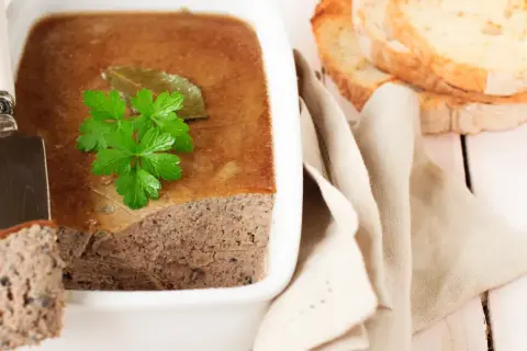 Terrine de campagne garnie de persil, prête à être dégustée avec des toasts. Une belle illustration de la différence entre terrine et pâté.