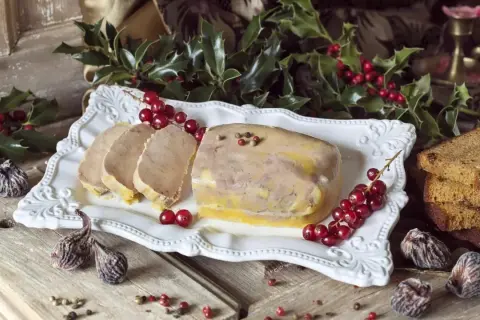 Un foie gras prêt à être dégusté pour Noël, accompagné de pain d'épices et de fruits secs. La question "quand faire le foie gras pour Noël" est résolue avec cette belle présentation.