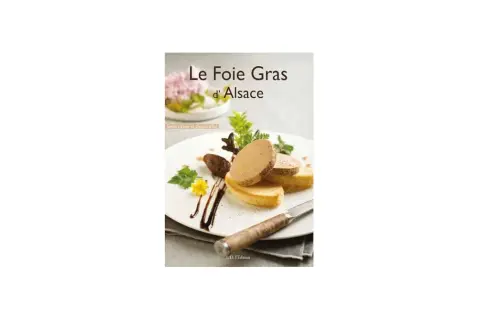 Tranches de foie gras sur toasts, garnies de verdure et d'une fleur jaune, sur une assiette blanche.