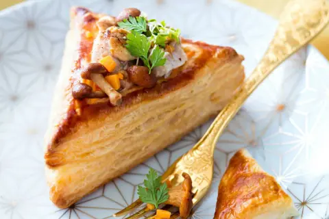 Délicieux feuilleté de ris de veau garni de champignons et de légumes croquants, servi sur une assiette ornée.