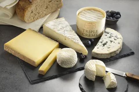Plateau de fromages variés, dont un bleu et un triple crème, accompagnés de pain artisanal. Un délice pour les amateurs de fromage fort en goût.