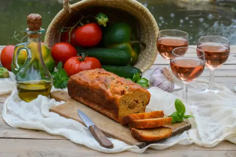 Un délicieux cake ratatouille, garni de légumes frais, d'huile d'olive et de vin rosé, prêt à être dégusté.