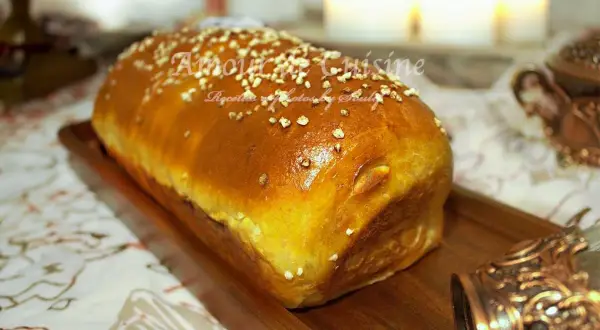 Un pain brioché salé doré, parsemé de graines, sur un plateau en bois. Parfait pour une recette facile et savoureuse.