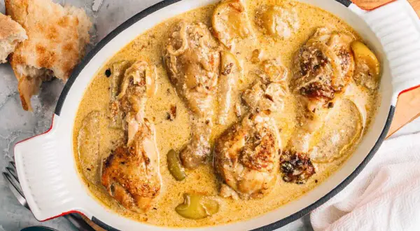 Poularde de Bresse en sauce crémeuse, une recette savoureuse avec des morceaux de poulet dorés et des pommes.
