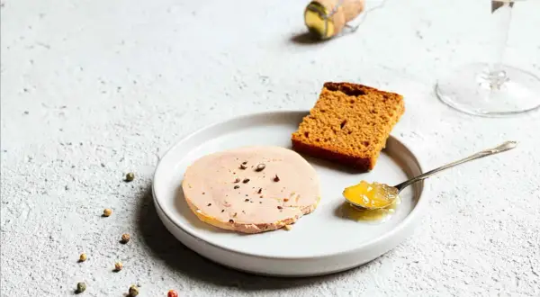 Tranche de foie gras sur assiette avec pain d'épices et confiture. La question "foie gras à partir de quel âge" reste ouverte.