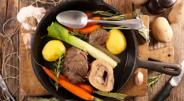 Un pot au feu savoureux, digne d'un journal des femmes, mijote dans une poêle en fonte avec des légumes et de la viande.