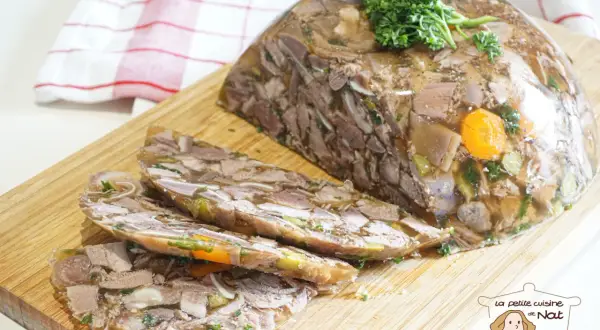 Tranche de fromage de tête, un plat traditionnel à base de viande et de légumes en gelée, garni de persil frais.