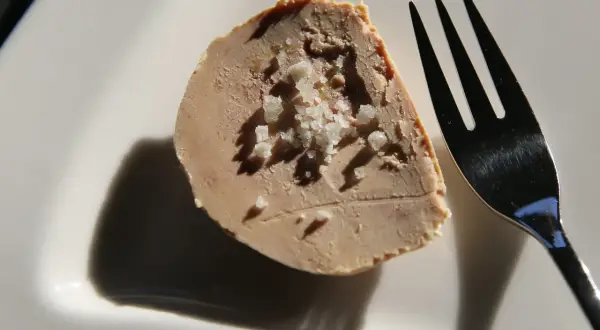Tranche de foie gras parsemée de gros sel, prête à être dégustée. Une touche d'acidité subtile pour un goût inoubliable.