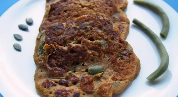 Galettes de patate douce sans gluten, parsemées de graines de courge, avec des haricots verts.