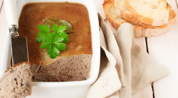 Terrine de campagne garnie de persil, prête à être dégustée avec des toasts. Une belle illustration de la différence entre terrine et pâté.