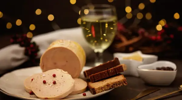 Foie gras maison servi avec du pain d'épices et une coupe de vin blanc. Quel alcool pour foie gras maison ? Un vin doux naturel ou un Sauternes serait parfait.