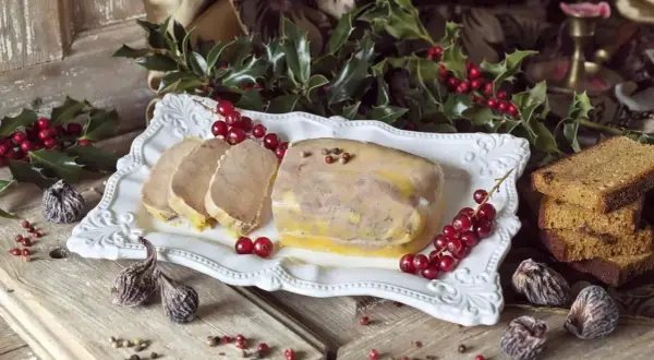 Un foie gras prêt à être dégusté pour Noël, accompagné de pain d'épices et de fruits secs. La question "quand faire le foie gras pour Noël" est résolue avec cette belle présentation.