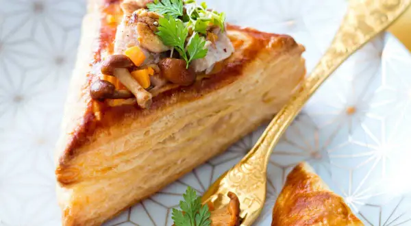 Délicieux feuilleté de ris de veau garni de champignons et de légumes croquants, servi sur une assiette ornée.