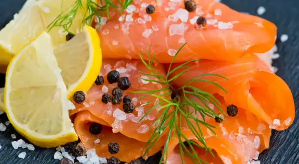 Une présentation de Noël : fines tranches de saumon fumé, parsemées de gros sel et de poivre, avec des quartiers de citron et de l'aneth.