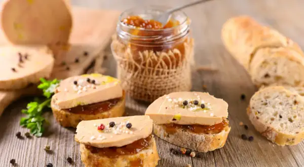 Tranches de pain garnies de foie gras et de confiture, avec un pain à côté. Le foie gras calories est un sujet de discussion, mais ce délice est irrésistible.