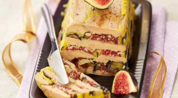 Un pressé de foie gras aux figues, une tranche est coupée, prête à être dégustée.