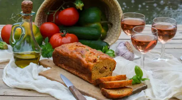 Un délicieux cake ratatouille, garni de légumes frais, d'huile d'olive et de vin rosé, prêt à être dégusté.