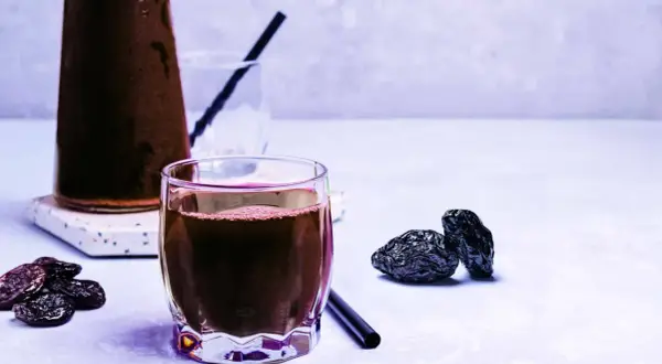 Un verre de jus de pruneau, quelques pruneaux secs et une carafe. Un vrai plaisir pour le temps d'un jus de pruneau.