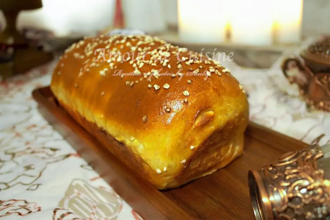 Un pain brioché salé doré, parsemé de graines, sur un plateau en bois. Parfait pour une recette facile et savoureuse.