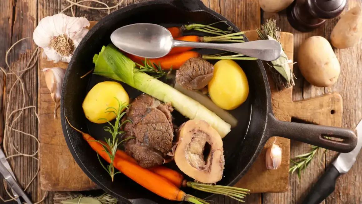 Un pot au feu savoureux, digne d'un journal des femmes, mijote dans une poêle en fonte avec des légumes et de la viande.