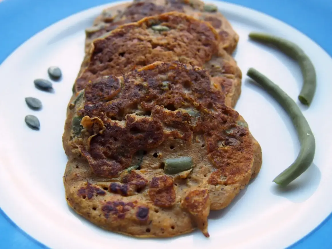 Galettes de patate douce sans gluten, parsemées de graines de courge, avec des haricots verts.