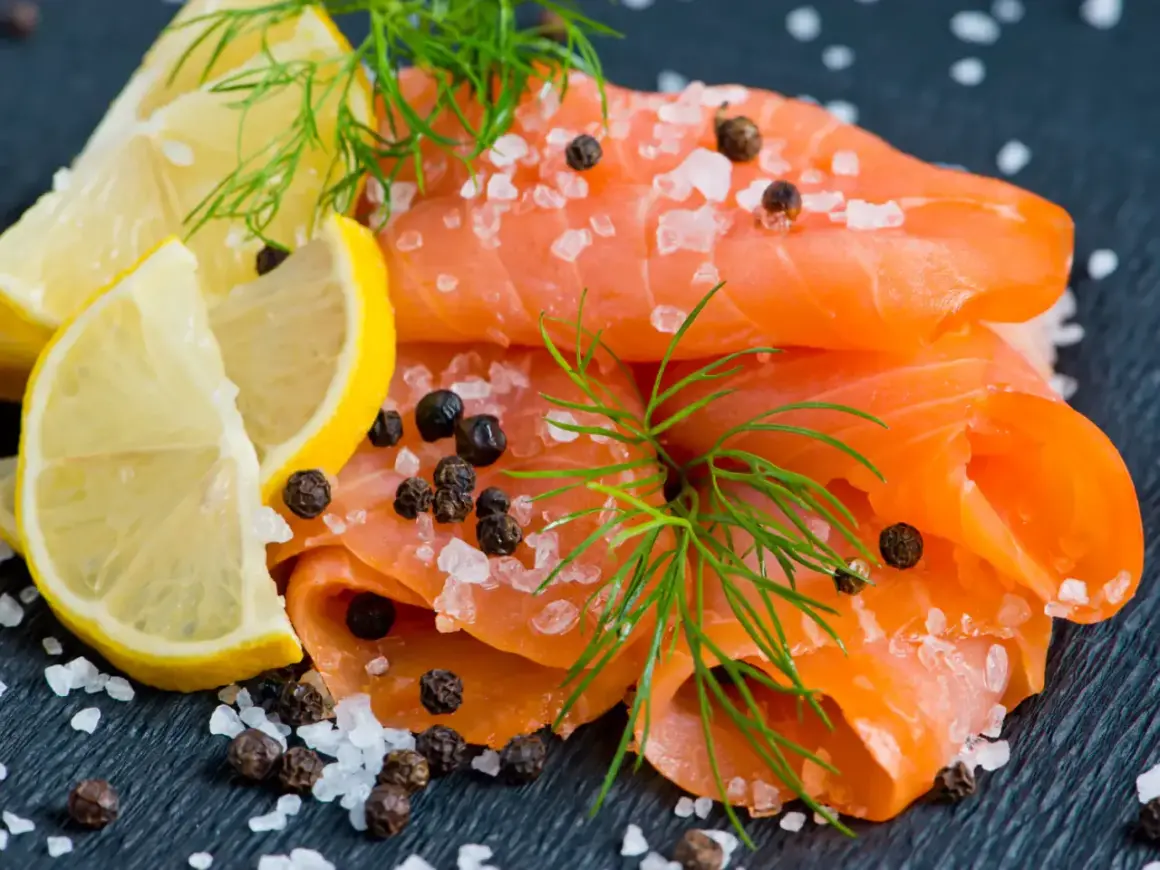 Une présentation de Noël : fines tranches de saumon fumé, parsemées de gros sel et de poivre, avec des quartiers de citron et de l'aneth.